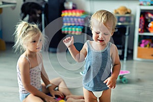 Two little siblings children quarrelling after playing at room at house. Crying offended toddler boy arguing with elder sister.