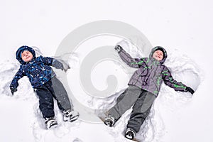 Two little siblings kid boys in colorful winter clothes making s