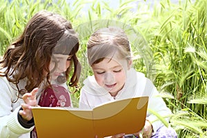 Two little sister girls reading book spikes garden