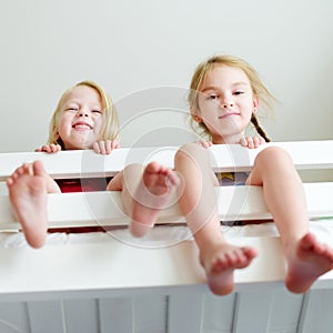 Two little sisters fooling around, playing and having fun in twin bunk bed