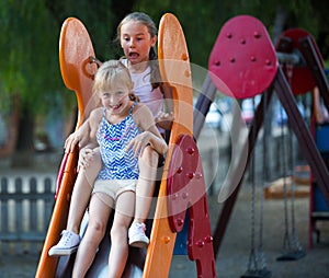 Two little sisters going down slide