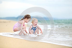 Two little sisters having fun on a beach