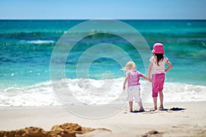 Two little sisters having fun on a sandy beach