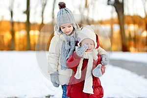 Two little sisters having fun on snowy winter day