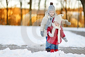 Two little sisters having fun on snowy winter day