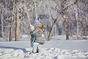 Two little sisters hug each other in snow in winter