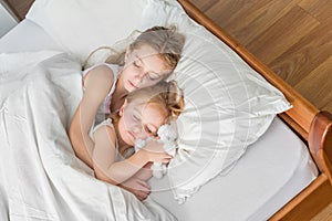 Two little sisters hugging in bed