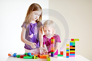 Two little sisters plaing with colorful blocks