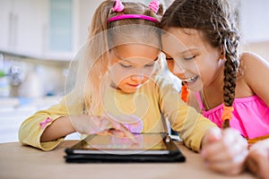 Two little sisters play on a Tablet PC