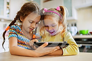 Two little sisters play on a Tablet PC