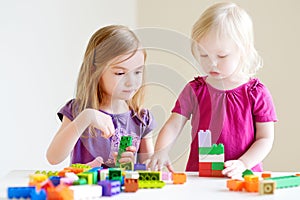 Two little sisters playing with colorful blocks