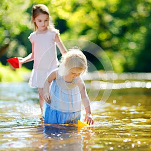 Two little sisters playing with paper boats