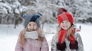 Two little sisters portrait in winter gesticulate with hands goodbye