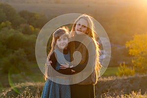 Two little sisters at sunset in the fall in nature.