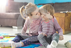 Two little sisters use tablet at home