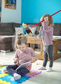 Two little sisters use tablet at home