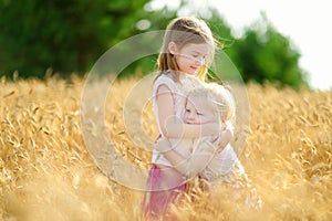 Two little sisters walking happily in wheat field
