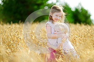 Two little sisters in wheat field on summer day