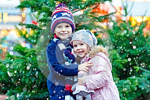 Two little smiling kids, boy and girl with christmas tree