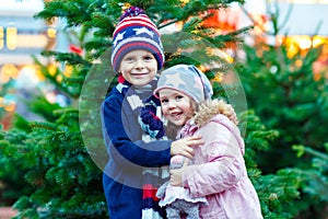 Two little smiling kids, boy and girl with christmas tree