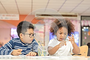 Two little toddler boy and girl enjoy drawing together. Two nationality children playing and learning together photo