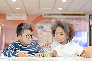 Two little toddler boy and girl enjoy drawing together. Two nationality children playing and learning together photo