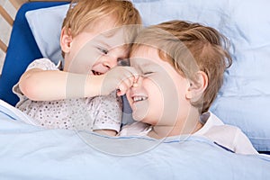 Two little toddler boys having fun in bed