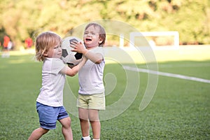 Two little toddler kids arguing at playground or stadium over soccer ball. Conflict management, hostile merger concept