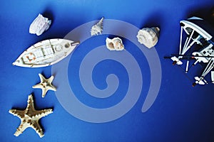 Two little toy ships and shells on a blue background. Top view. Copy space