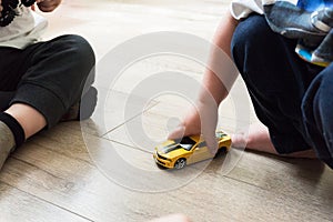 Two Little young caucasian boys plays with colorful yellow toy cars indoors.