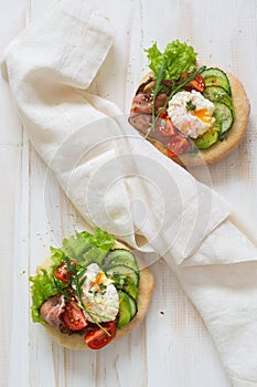 Two loaf of bread with poached eggs and fresh vegetables