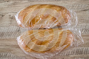 Two loaves in a plastic bag on a wooden background. Close-up. White Ukrainian bread.