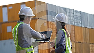 Two logistic staff discussing while checking and control loading containers box from cargo.