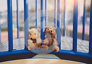 Two lost teddy bear lying on metal bridge at playground in gloomy day, Lonely and sad face brown bear doll lied down in the park,