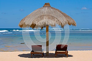 Two lounge chairs under tent on beach