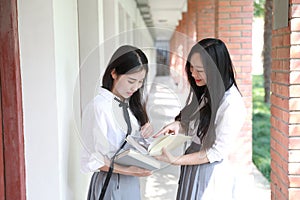 Two lovely Asian Chinese pretty girls wear student suit in school best friends smile laugh reading book in nature