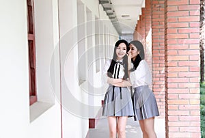 Two lovely Asian Chinese pretty girls wear student suit in school best friends smile laugh talking and gossip