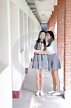 Two lovely Asian Chinese pretty girls wear student suit in school best friends smile laugh talking and gossip