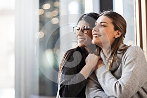 Two lovely girls in a cafe. Female friends hugging and looking outside the window