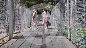 Two lovely sisters walk down a fenced wooden walkway to feed the deer at the zoo. Spending great time with her family on vacation.