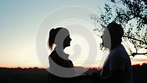 Two lovers boy and girl standing on the high Bank of the river against the beautiful sunset and look at each other.