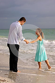 Two lovers holding hands and talking at the beach