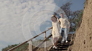 Two lovers running downstairs seashore near hill. Laughing woman outpace of guy.