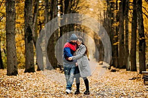 Two lovers walk along an alley in an autumn park and hug each other. Autumn, love, a romantic date