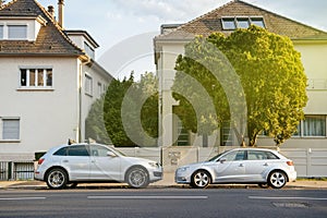 Two luxury AUDi cars parked in front of the large houses
