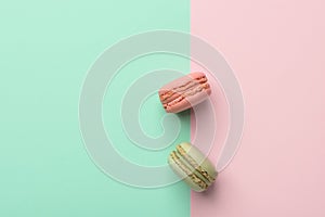 Two macarons strawberry and pistachio flavor on duotone pastel green chartreuse pink background. French pastry confectionery photo