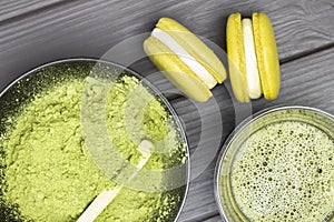 Two macarons and vatcha tea in bowl. Green matcha tea powder in black bowl