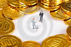 Two macro dolls negotiating in golden coins