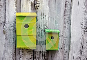 two made wooden and painted birdhouses hang on the white wall in the garden