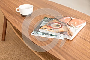 Magazines and coffee mug on the table, real photo